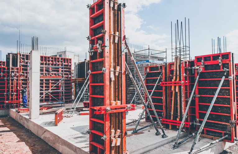 À propos de nous 2 Systèmes de coffrage modulaires rouges et structures d'armature en acier assemblés sur une fondation en béton sur un chantier de construction.